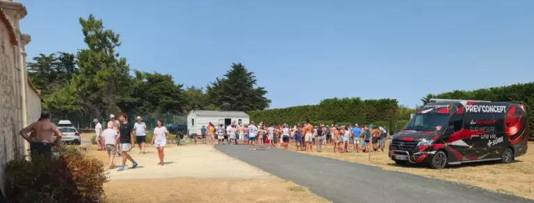 Vacanciers rassemblés au point de rassemblement d’un camping lors d’un exercice d’évacuation, à côté du véhicule Prev’Concept