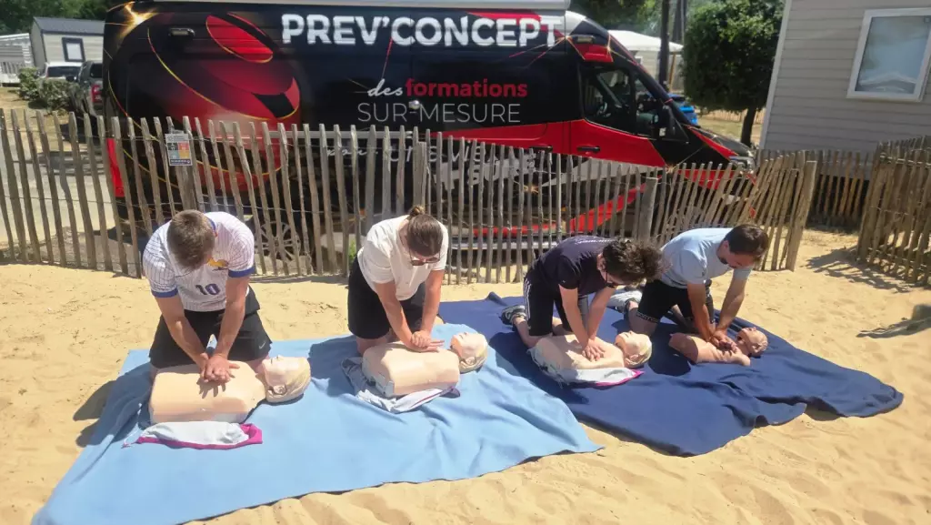 Stagiaires pratiquant le massage cardiaque sur mannequins dans un camping, devant le véhicule Prev’Concept